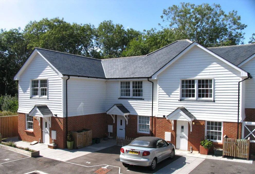 Pair of new build houses with white weatherboarding and tiled roofs